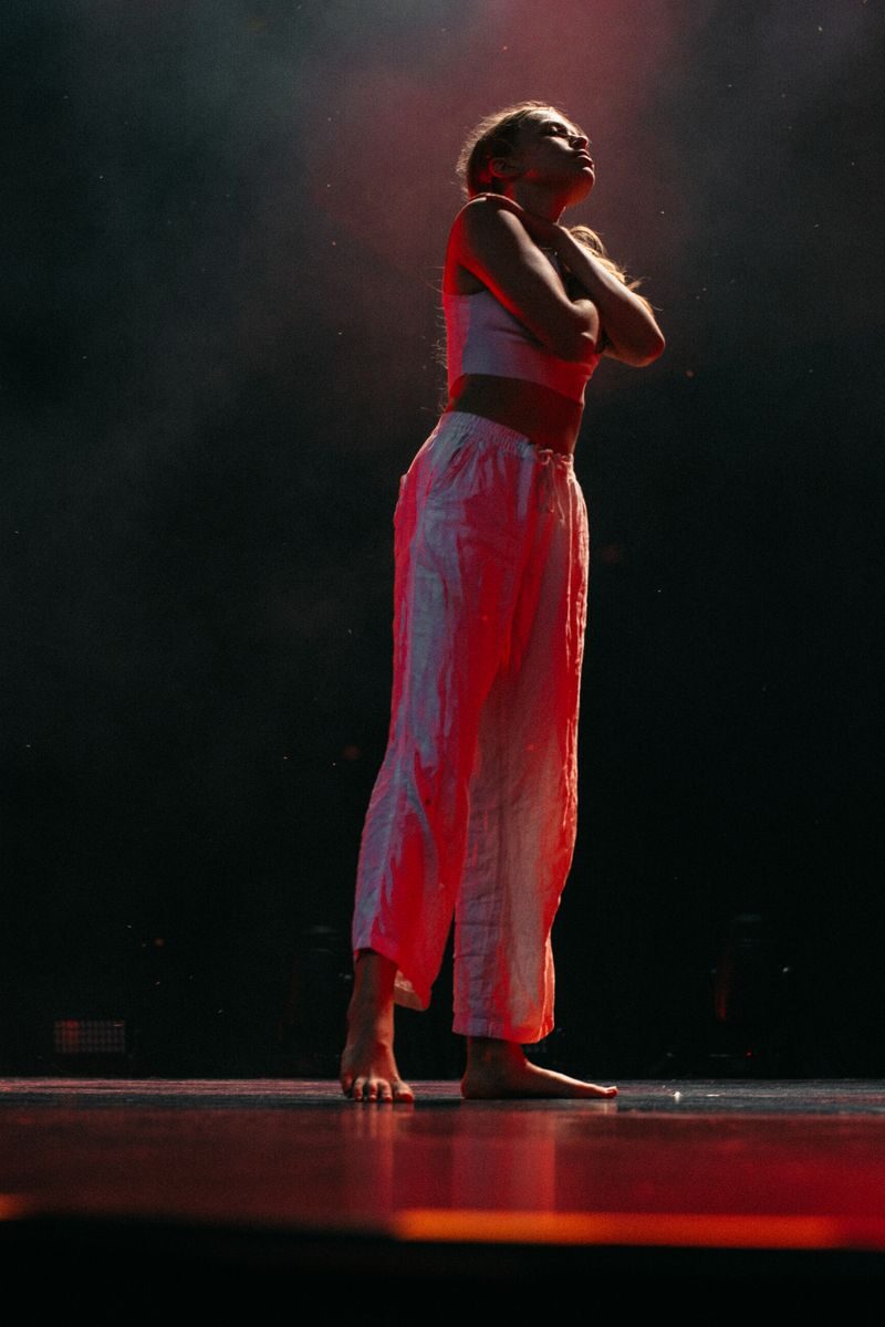 Artistic expression through dance captured in dramatic lighting on a dark stage.