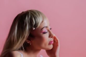 Portrait of a woman showcasing elegant beauty against a pastel pink background.