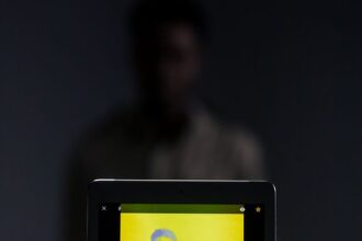 A digital portrait of a man on a tablet screen with a dramatic yellow color filter.