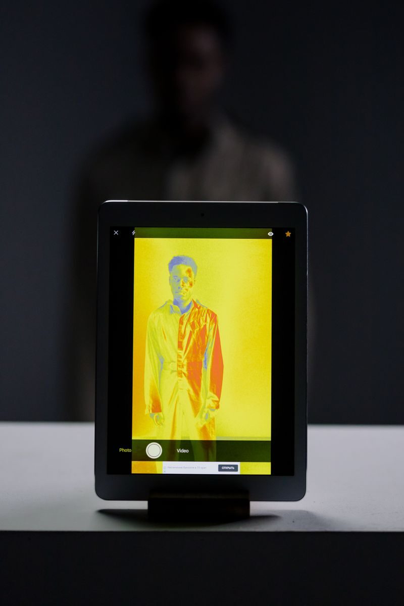 A digital portrait of a man on a tablet screen with a dramatic yellow color filter.