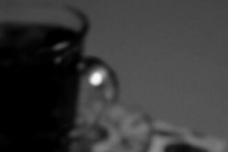 Black and white cozy scene with a lit candle next to a teacup, creating a warm atmosphere.